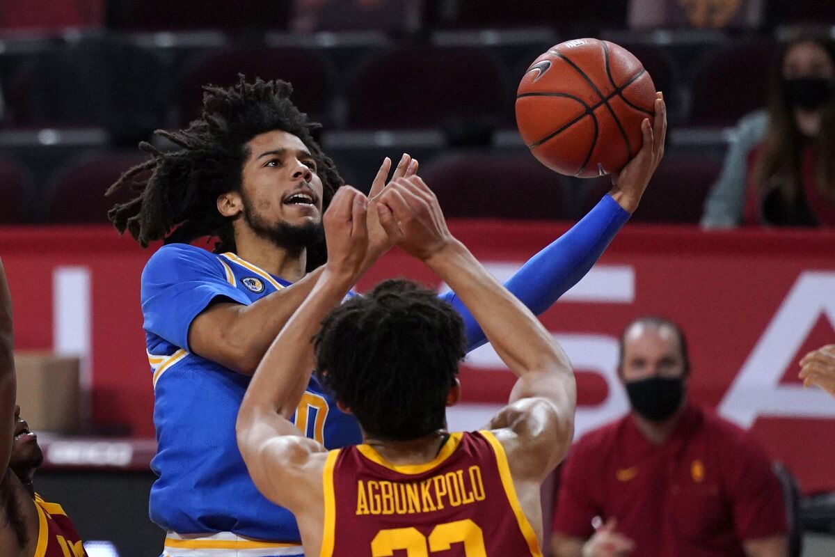 UCLA guard Tyger Campbell, left, shoots as USC forward Max Agbonkpolo defends Feb. 6, 2021, in Los Angeles.