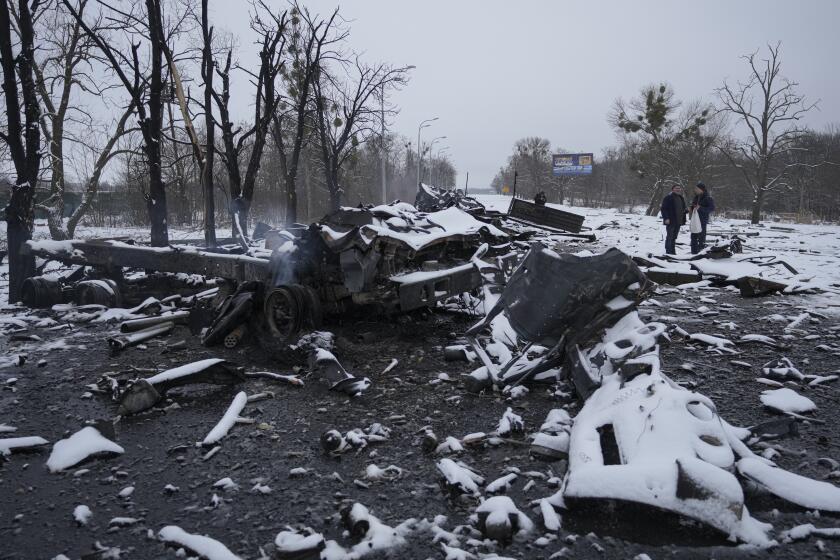 People walk by smoldering destroyed Russian military vehicles on the outskirts of Kharkiv, Ukraine, Friday, Feb. 25, 2022. Russian troops bore down on Ukraine's capital Friday, with gunfire and explosions resonating ever closer to the government quarter, in an invasion of a democratic country that has fueled fears of wider war in Europe and triggered worldwide efforts to make Russia stop. (AP Photo/Vadim Ghirda)