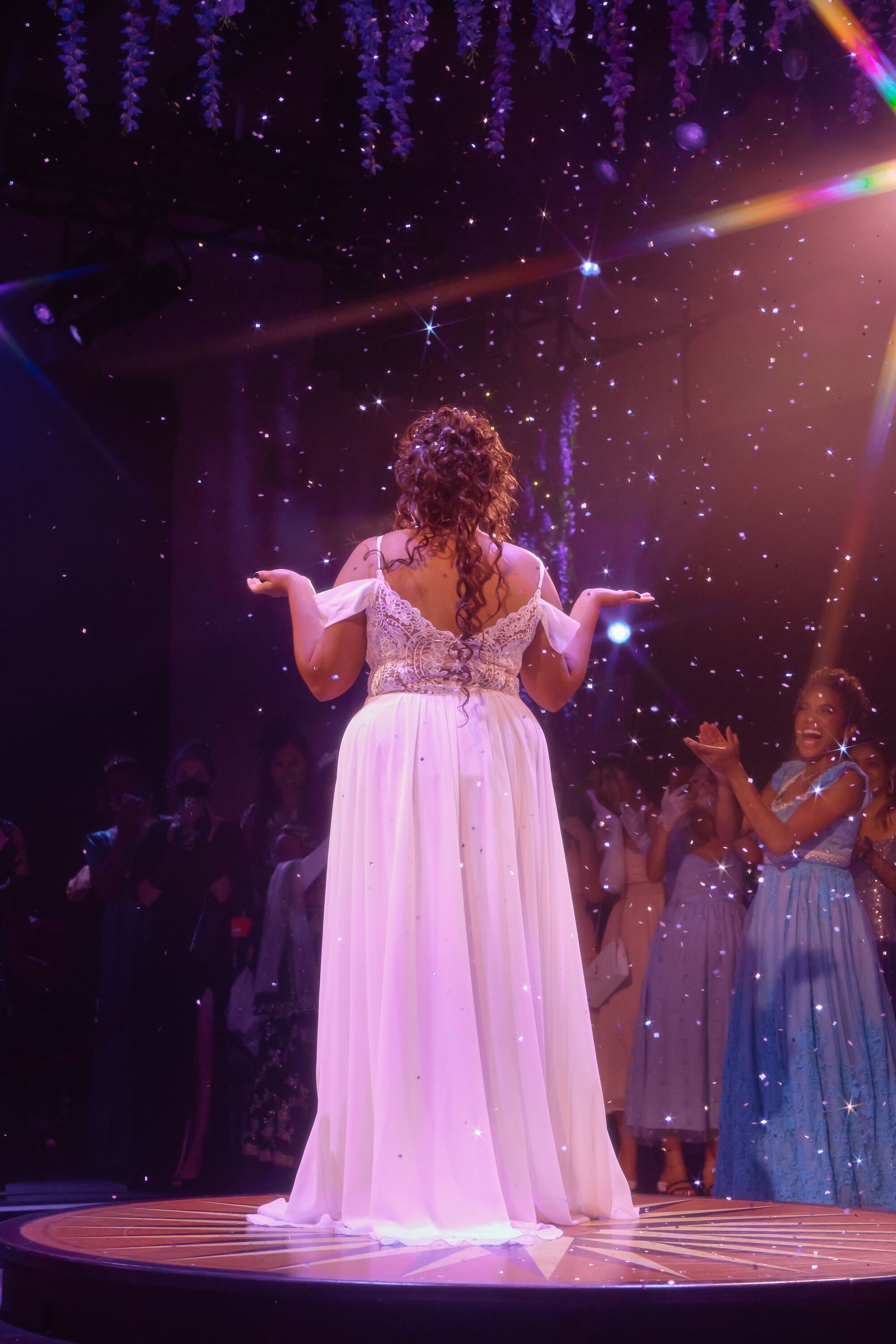 A woman in evening dress is in the spotlight.