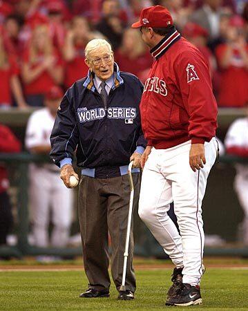 Wooden, who was a big baseball fan, walks with Angels Manager Mike Scioscia on his way to throwing out the first pitch at a World Series game in Anaheim in 2002.