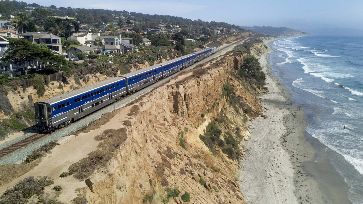 An Amtrak Surfliner train travels along eroding sandstone cliffs in Del Mar, Calif.