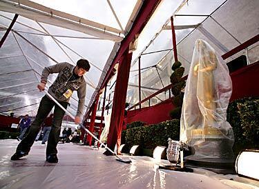 Danny Crescenti, a production assistant for the Oscar red carpet pre-show, tries to keep water off the plastic covering the red carpet as workers continue preparing for Sunday evening's telecast of the Academy Awards.
