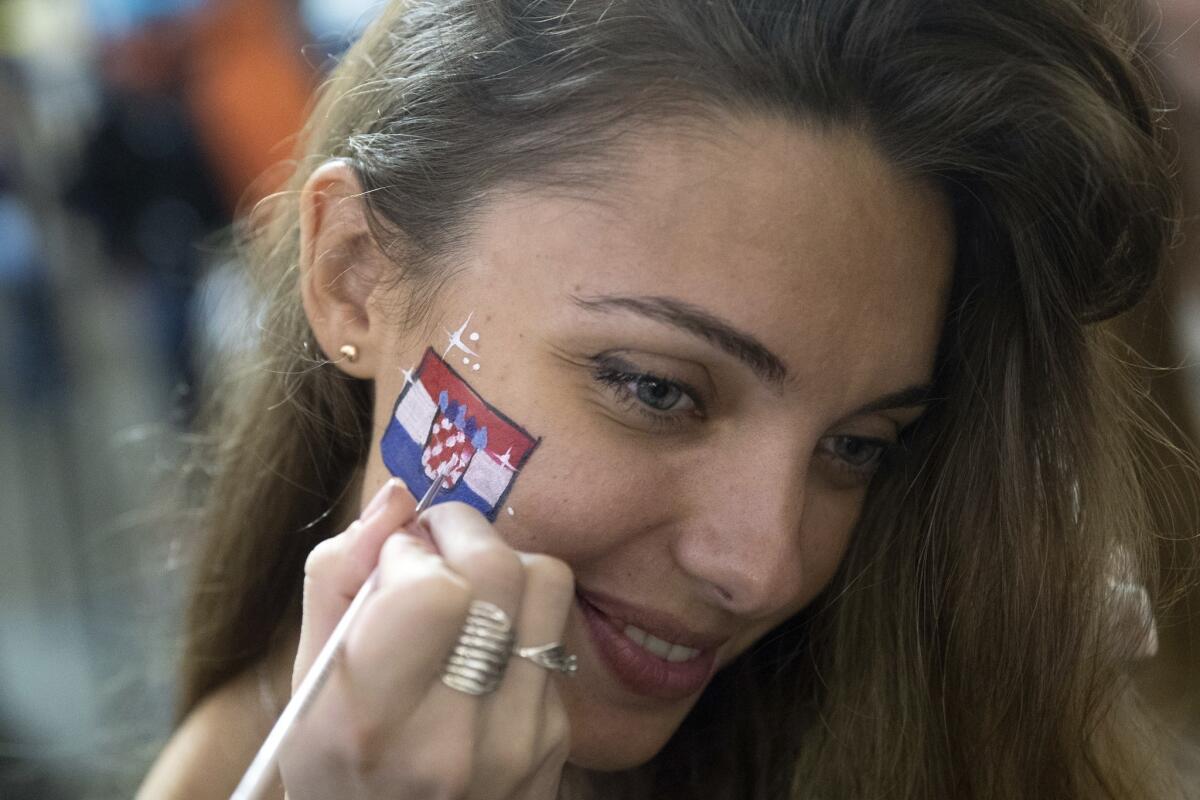 Russia's soccer fan is painted her face in Croatia's national flag after Croatia won the semifinal soccer match between Croatia and England during the 2018 soccer World Cup at the Luzhniki stadium, in Nikolskaya street near the Kremlin in Moscow, Russia, early Thursday, July 12, 2018.