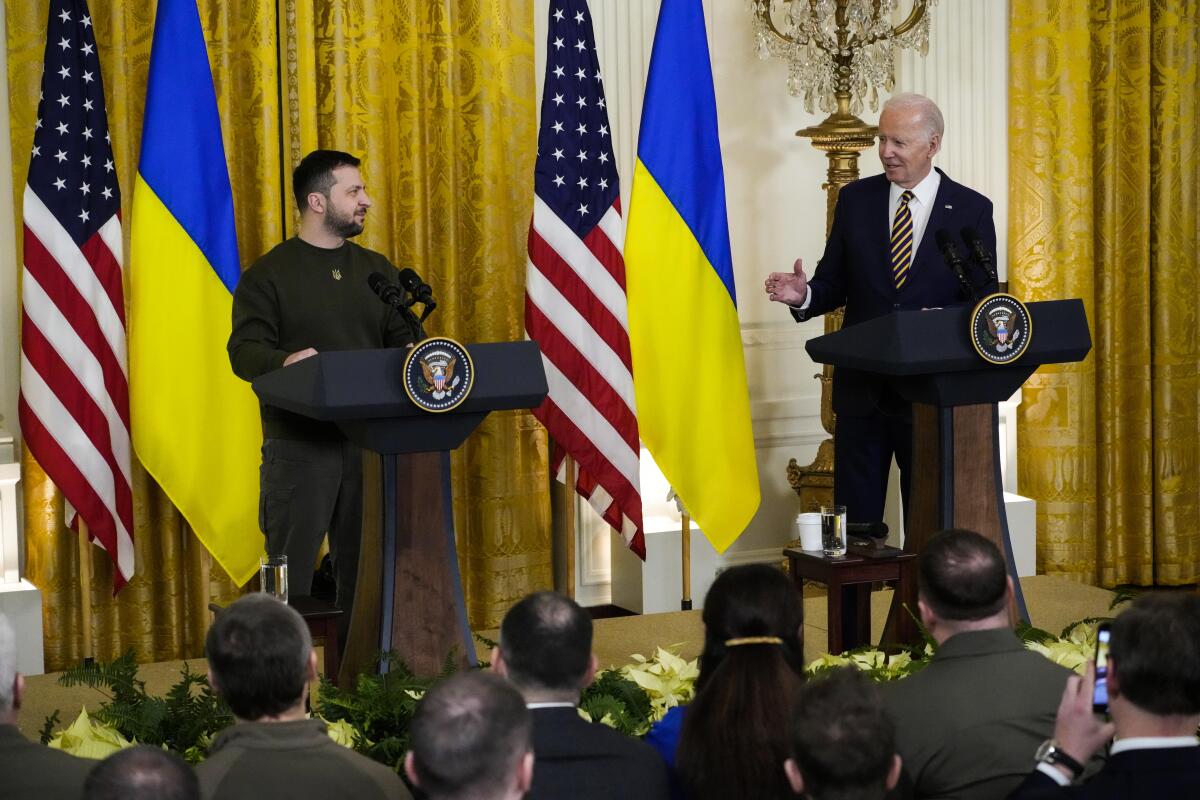 U.S. President Biden and President of Ukraine Volodymyr Zelensky stand in front of two podiums in front of a crowd 