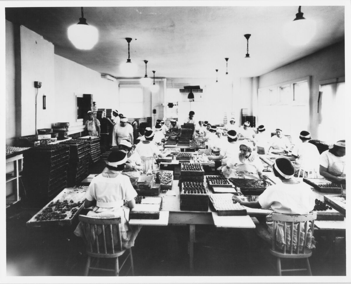 A black and white photograph of women working with See's Candies