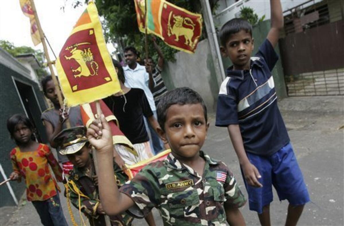 A Sri Lankan child dressed in a camouflage costume shows a national flag as children celebrate the military victory over Tamil Tiger rebels in Colombo, Sri Lanka, Wednesday, May 20, 2009. Sri Lanka's president has reached out to the Tamil minority, calling for political compromise to unify this island nation after the defeat of the Tamil Tiger rebel group and the death of its leader. (AP Photo/Eranga Jayawardena)