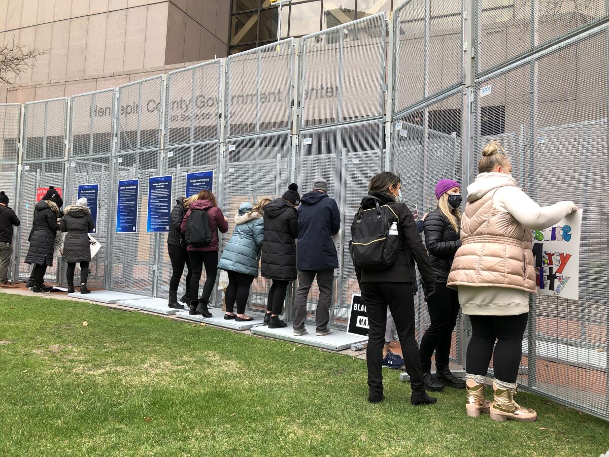 People read and affix signs to chainlink fence.