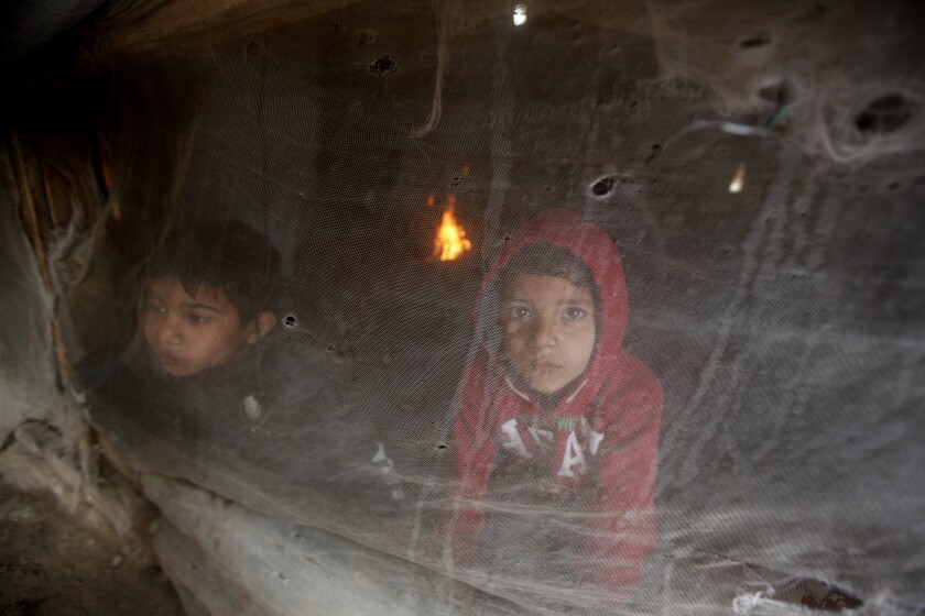 Syrian boys look through their tent window as they try to stay warm at a refugee camp.
