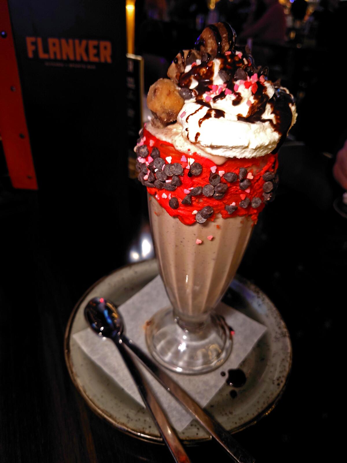 A milkshake with whipped cream and chocolate sauce on top