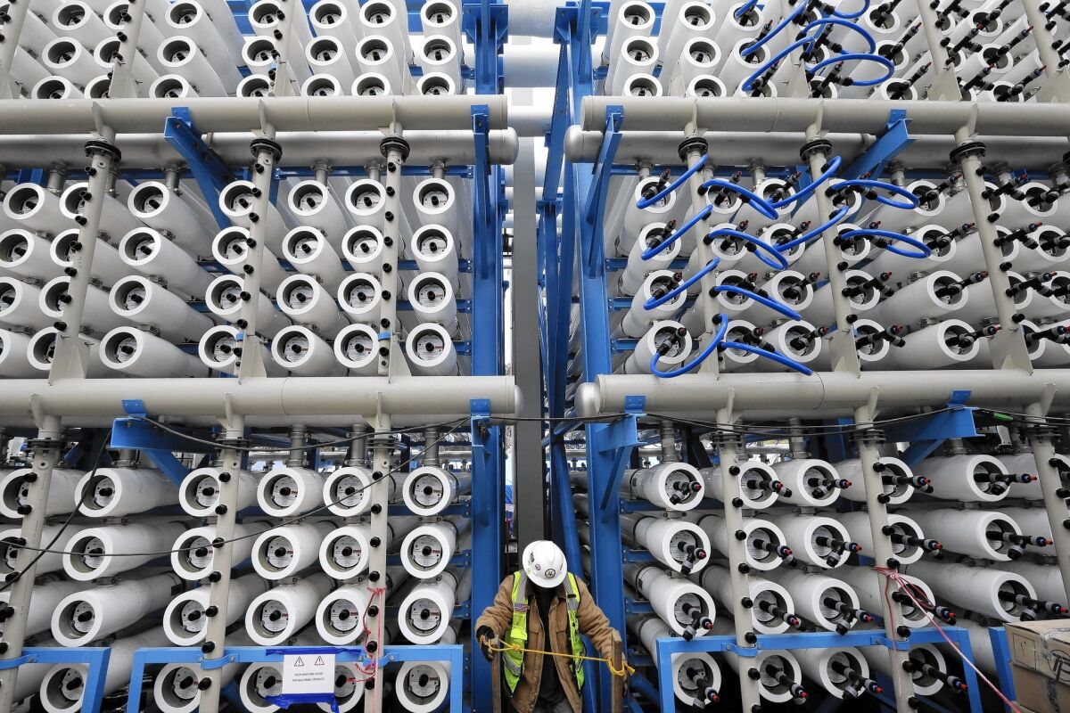 A worker climbs stairs among pressure vessels that convert seawater into fresh water at the Carlsbad desalination plant.