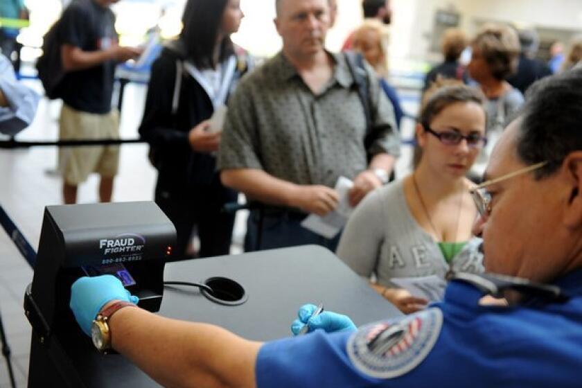 A TSA agent checks an identification card at LAX. In the wake of Friday's fatal shooting of a TSA screener at the airport, specialists on hate crimes and union officials decried what they say is a general atmosphere of mockery and derision toward TSA agents.