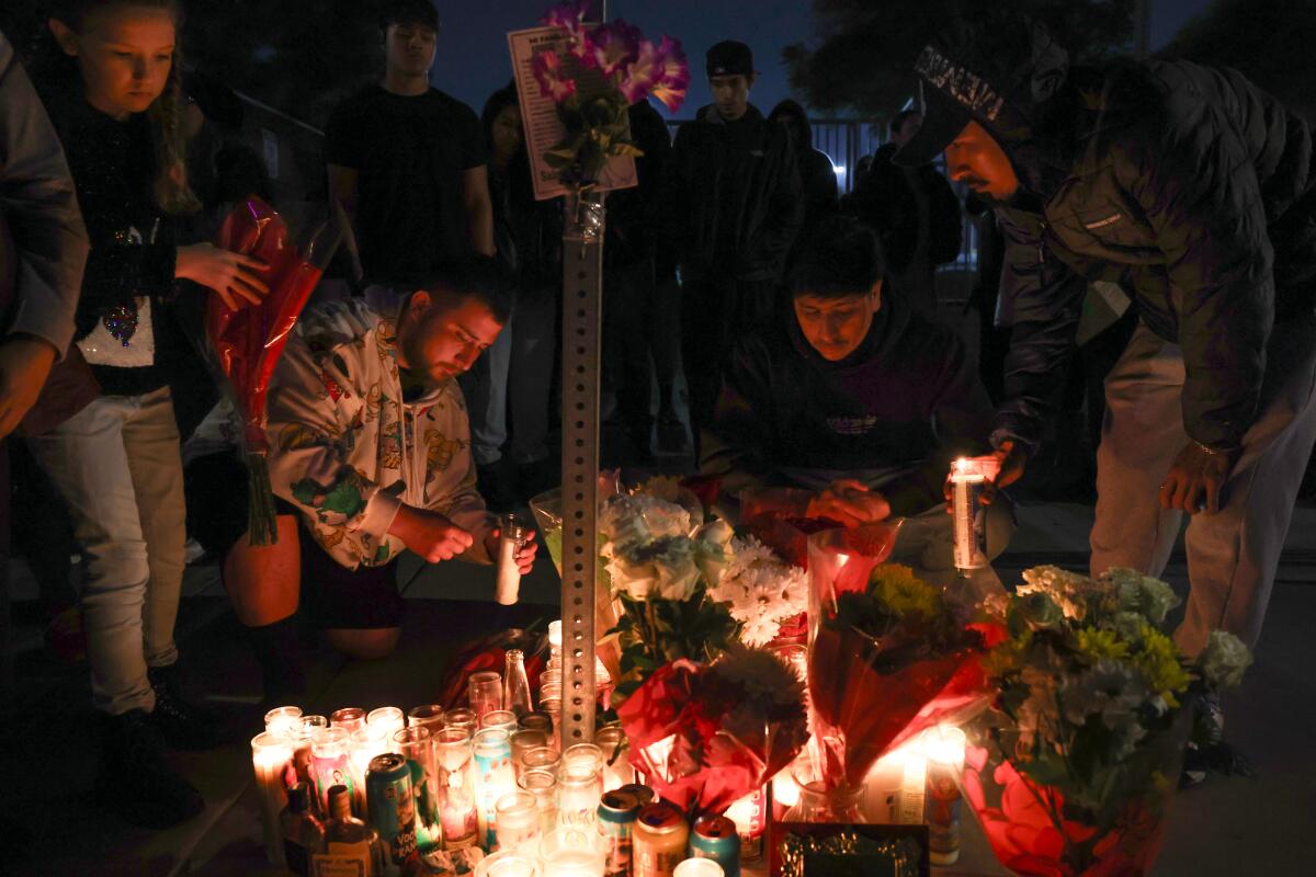 A man lights candles alongside others during a vigil in Bell