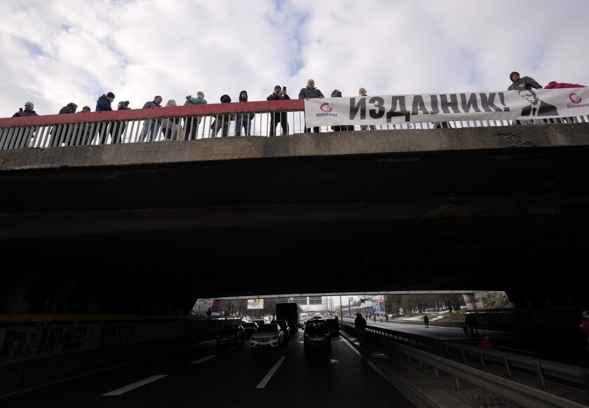 Environmental demonstrators hold banner showing an image of Serbian President Aleksandar Vucic, reading: "A traitor!" as they block a highway during a protest in Belgrade, Serbia, Saturday, Jan. 15, 2022. Hundreds of environmental protesters demanding cancelation of any plans for lithium mining in Serbia took to the streets again, blocking roads and, for the first time, a border crossing. Traffic on the main highway north-south highway was halted on Saturday for more than one hour, along with several other roads throughout the country, including one on the border with Bosnia. (AP Photo/Darko Vojinovic)