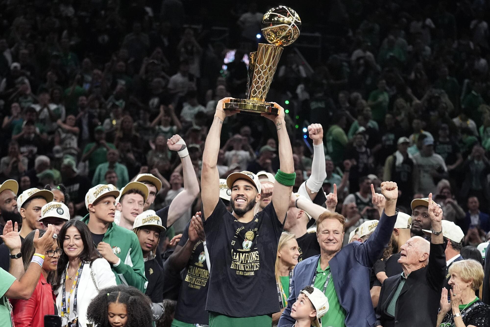 Boston forward Jayson Tatum, center, holds the Larry O'Brien Trophy as he celebrates with his Celtics teammates.