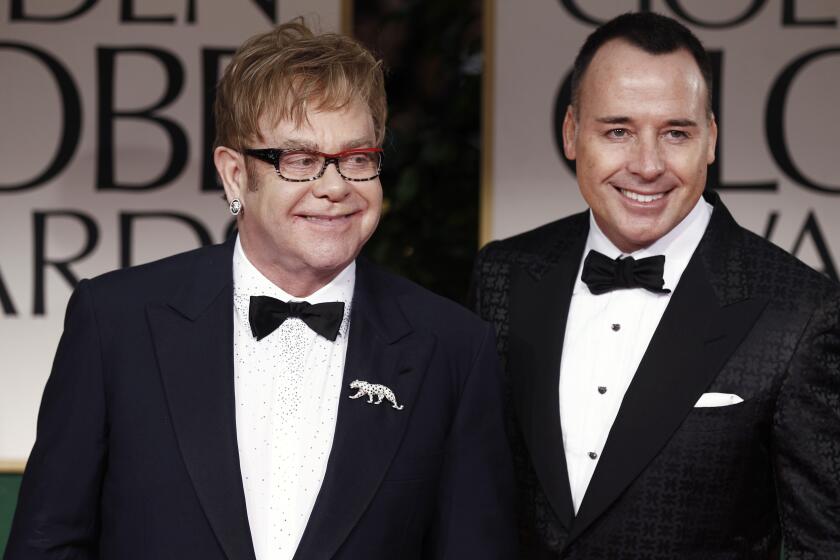 FILE - Elton John, left, and David Furnish arrive at the 69th Annual Golden Globe Awards Sunday, Jan. 15, 2012, in Los Angeles. A new exhibition of photographs owned by Elton John opens this week at London’s Victoria and Albert Museum. It includes more than 300 pieces by 140 photographers selected from the vast collection of John and his husband David Furnish. (AP Photo/Matt Sayles, File)