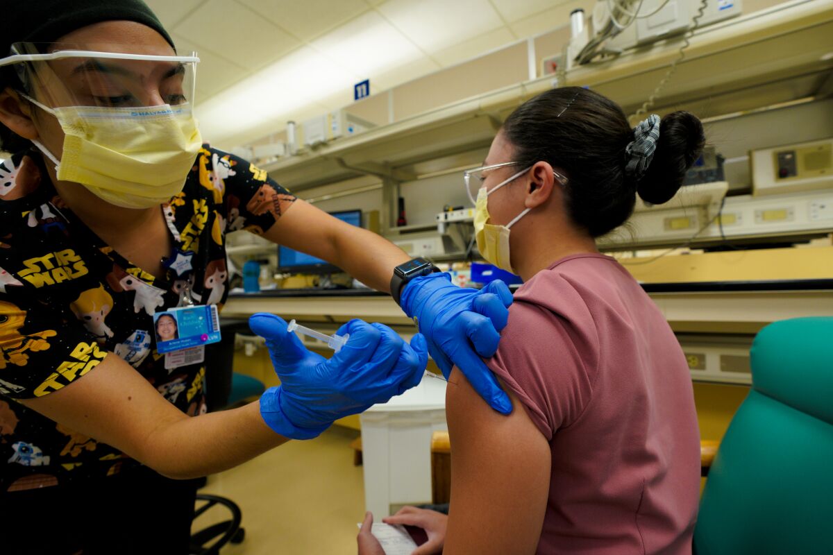 Arlene Huezo, LVN inoculates Hazel Reyes, Medical Assistant with the COVID-19 Moderna vaccine.