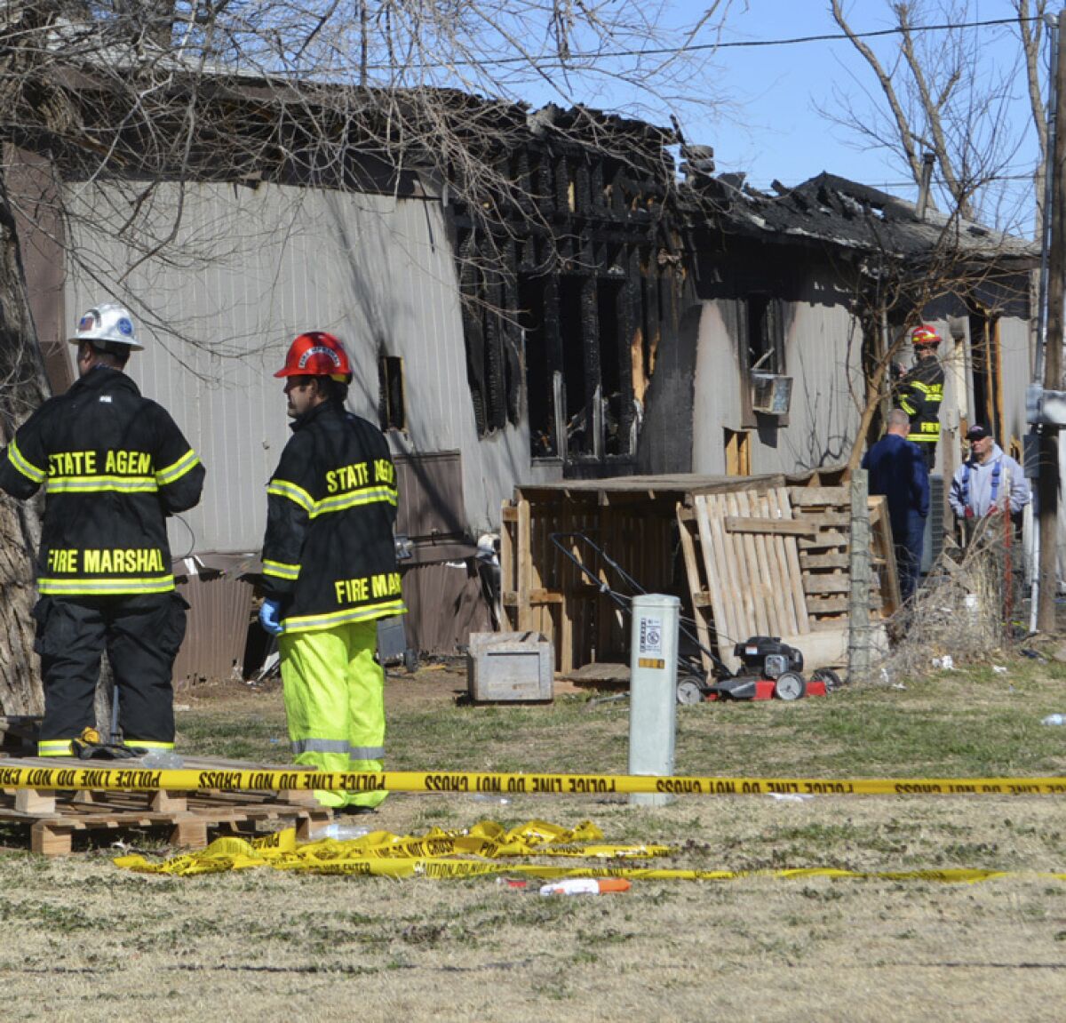Investigators from the State Fire Marshal's office go over the site of a multi-fatality mobile home fire in Woodward, Okla., Wednesday, March 3, 2021. Officials say six people, including some children, are dead after a fire swept through the home. Fire Chief Todd Finley says one boy escaped the blaze early Thursday morning after a firefighter and a bystander were able to free him from a window. (Dawnita Fogleman/The Woodward News via AP)