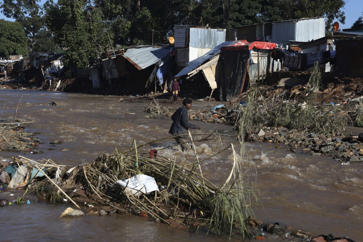 A man crosses a river at an informal settlement during flooding in Durban, South Africa, Thursday, April 14, 2022. Heavy rains and flooding have killed at least 341 people in South Africa's eastern KwaZulu-Natal province, including the city of Durban, and more rainstorms are forecast in the coming days. (AP Photo/Str)