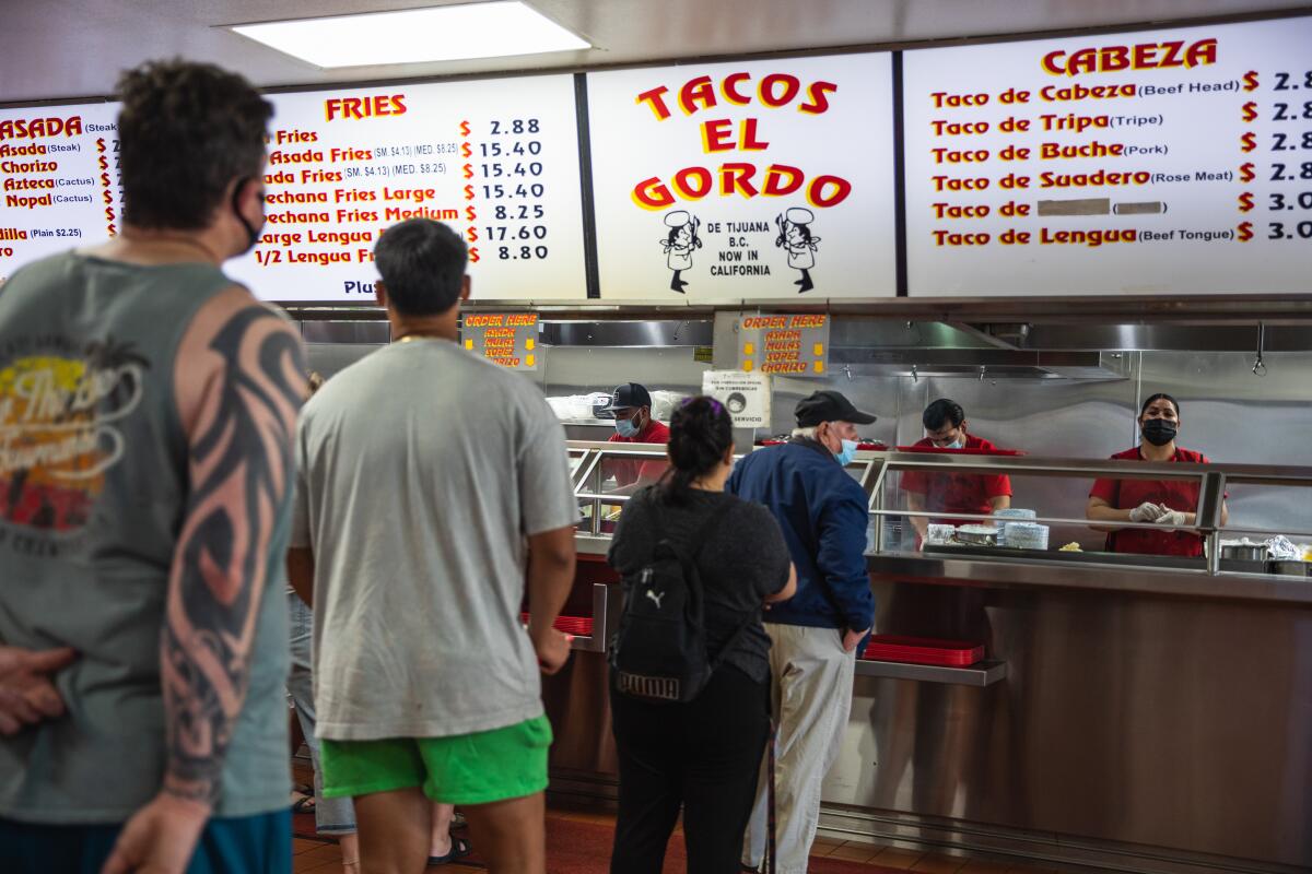 Los clientes esperan en la fila para pedir comida en Tacos El Gordo en Chula Vista el jueves 3 de junio.