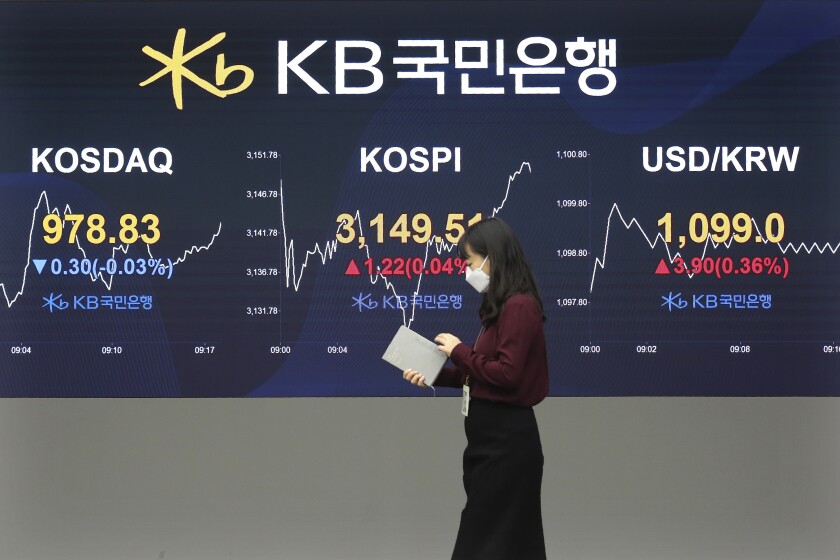 A currency trader passes by monitors showing the Korea Composite Stock Price Inde, and foreign exchange rate at the foreign exchange dealing room of a KB Kookmin Bank branch in Seoul, South Korea, Thursday, Jan. 14, 2021. Shares were mostly higher in Asia on Thursday after a lackluster day on Wall Street, where major indexes spent the day drifting up and down near their record highs. (AP Photo/Ahn Young-joon)