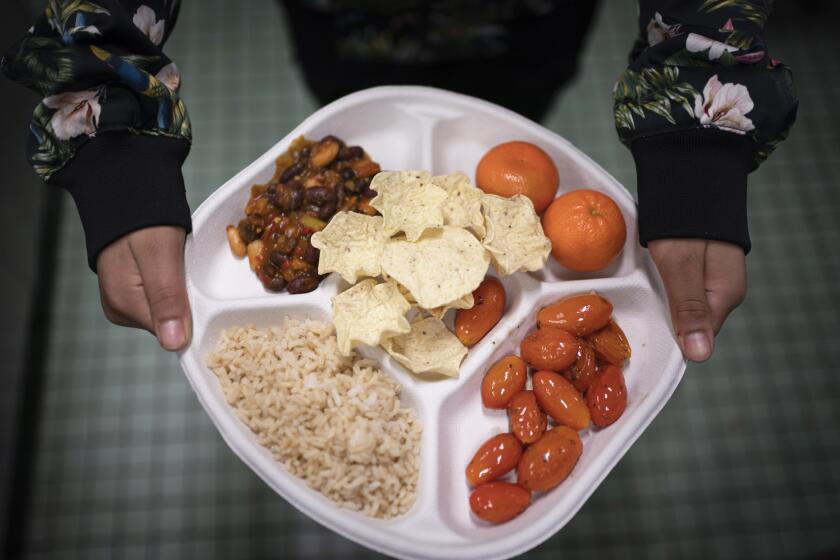 ARCHIVO - Una alumna de séptimo grado lleva su plato vegano, el cual consiste de chili con frijoles, arroz, mandarinas, tomates cereza y papitas horneadas, durante su descanso para almorzar en una escuela pública, el viernes 10 de febrero de 2023, en el distrito de Brooklyn, Nueva York. (AP Foto/Wong Maye-E, archivo)