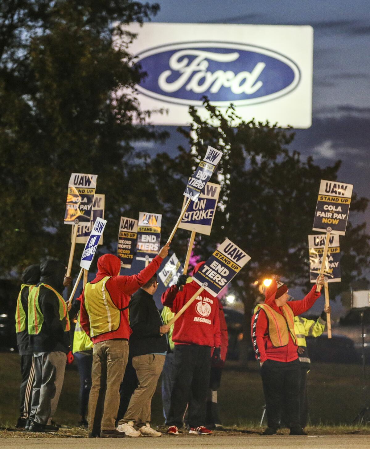 Autoworkers hold picket signs in front of a Ford plant