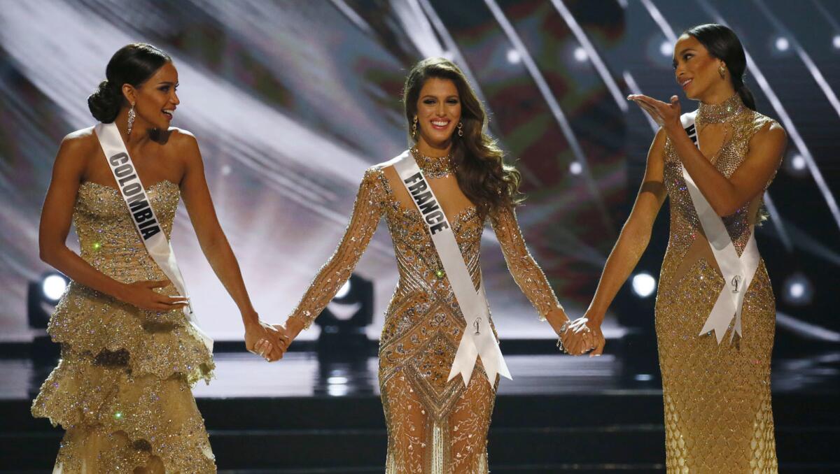 Miss France Iris Mittenaere, center, holds hands with Miss Colombia Andrea Tovar, left, and Miss Haiti Raquel Pelissier before the the Miss Universe is announced.