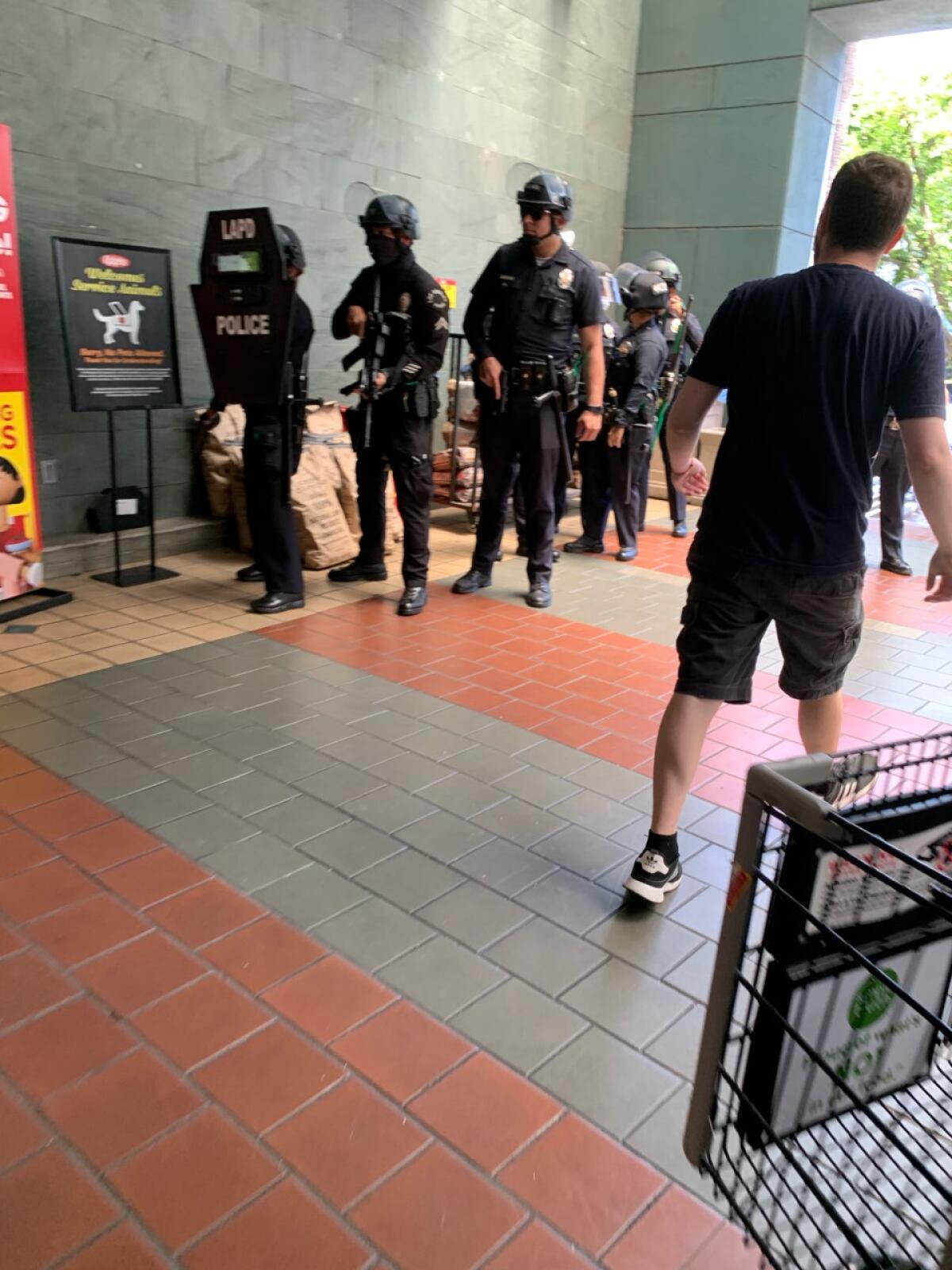 Armed LAPD officers stand beside a Ralphs sign