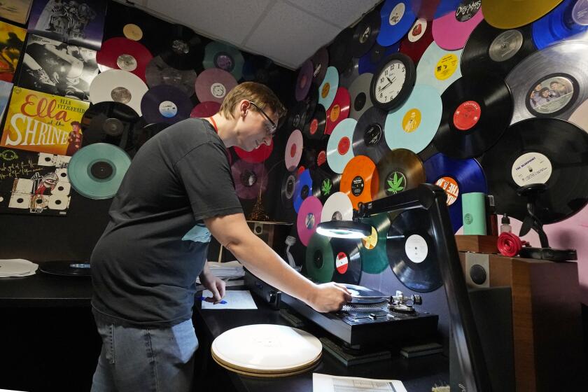 Tyler Bryant escucha discos de vinilo terminados en busca de fallas, en una sala de control de calidad en las instalaciones de United Record Pressing, el jueves 23 de junio de 2022 en Nashville, Tennessee. (Foto AP/Mark Humphrey)