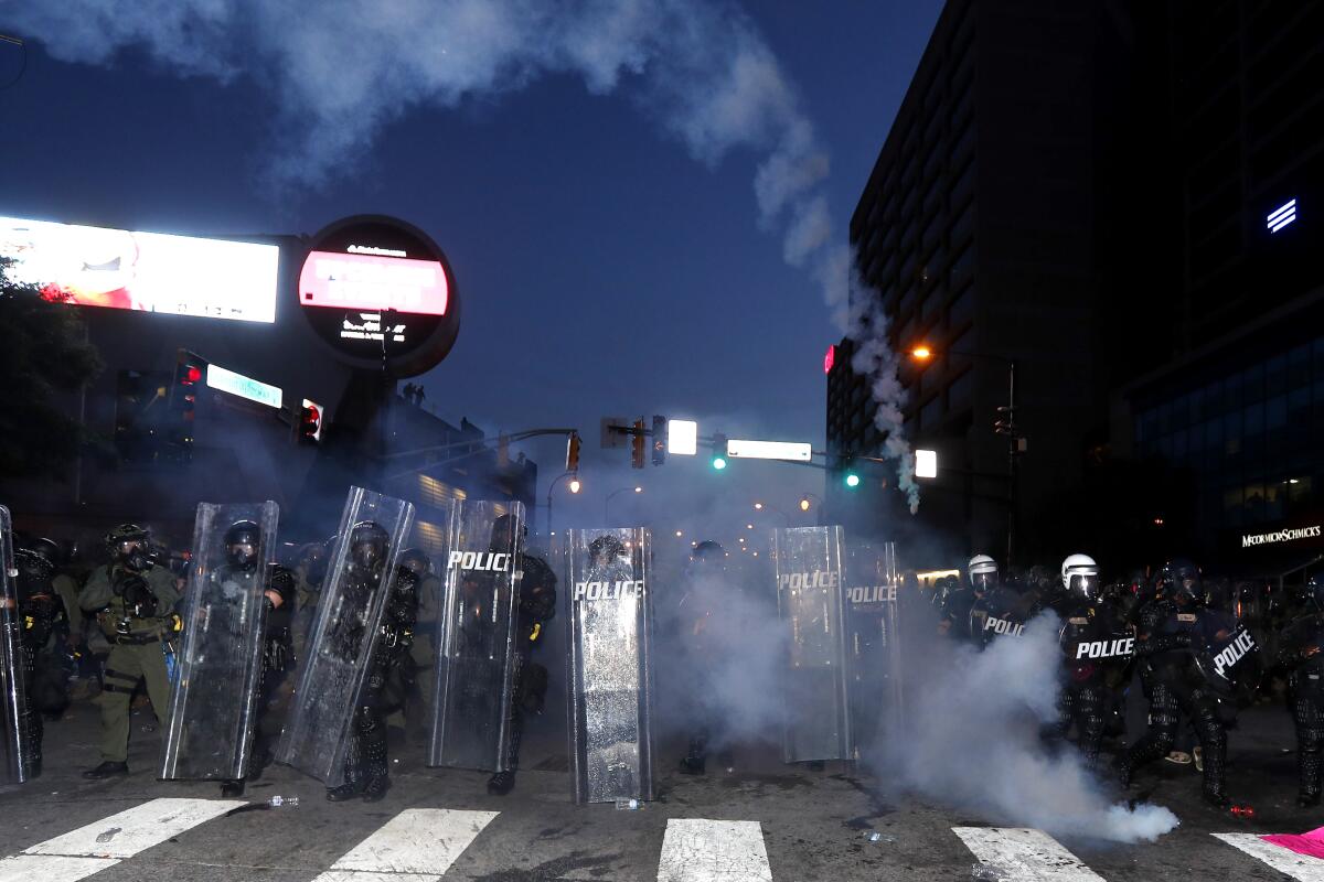 Police prepare to enforce a curfew with gas as demonstrators chant in Atlanta on Tuesday.