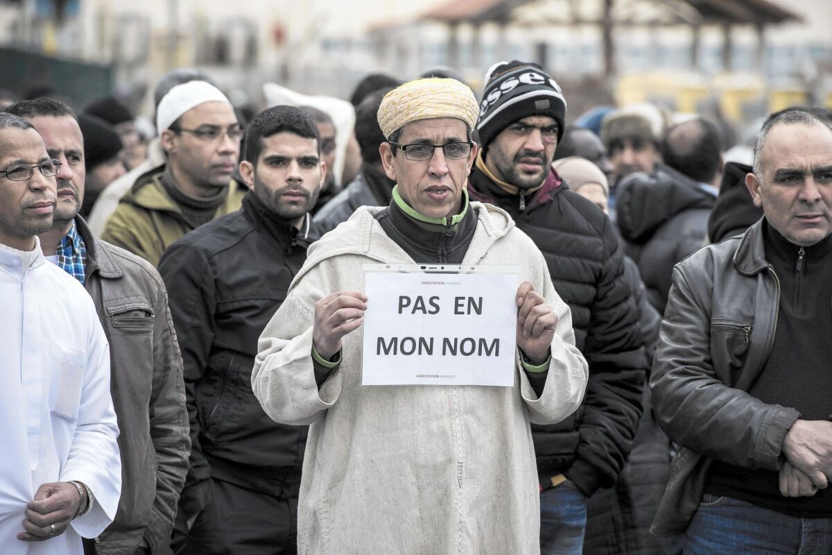 A Muslim man at a gathering near a mosque in Saint-Etienne, France, holds a sign reading "Not in my name" after the deadly attack on the satirical magazine Charlie Hebdo.