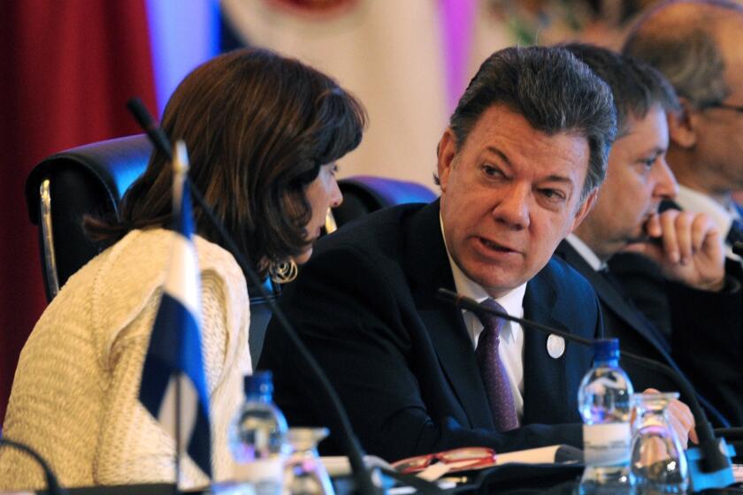 Colombian President Juan Manuel Santos speaks with Foreign Minister Maria Angela Holguin during the Ibero-American Summit in Panama City last month.
