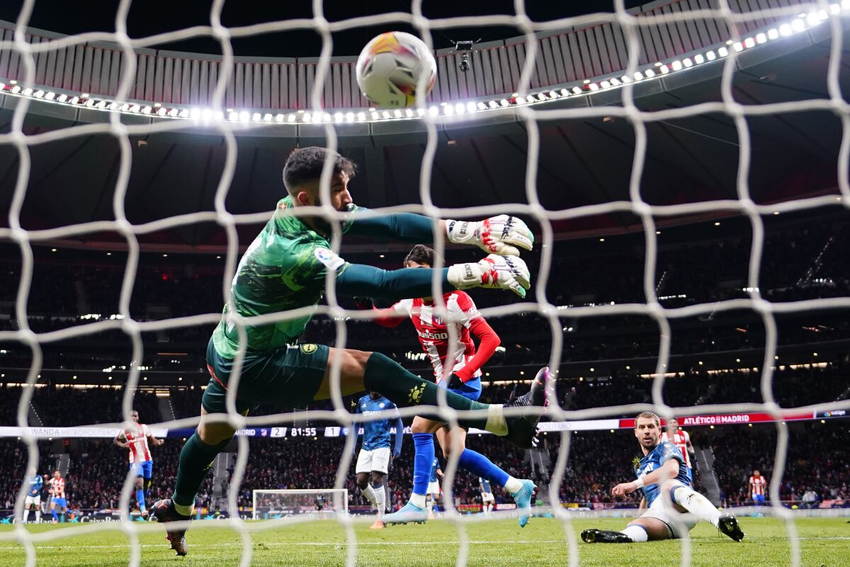 Alaves' goalkeeper Fernando Pacheco, left, misses a goal by Atletico Madrid's Joao Felix, center, during a Spanish La Liga soccer match between Atletico Madrid and Alaves at the Wanda Metropolitano stadium in Madrid, Spain, Saturday, April 2, 2022. (AP Photo/Manu Fernandez)