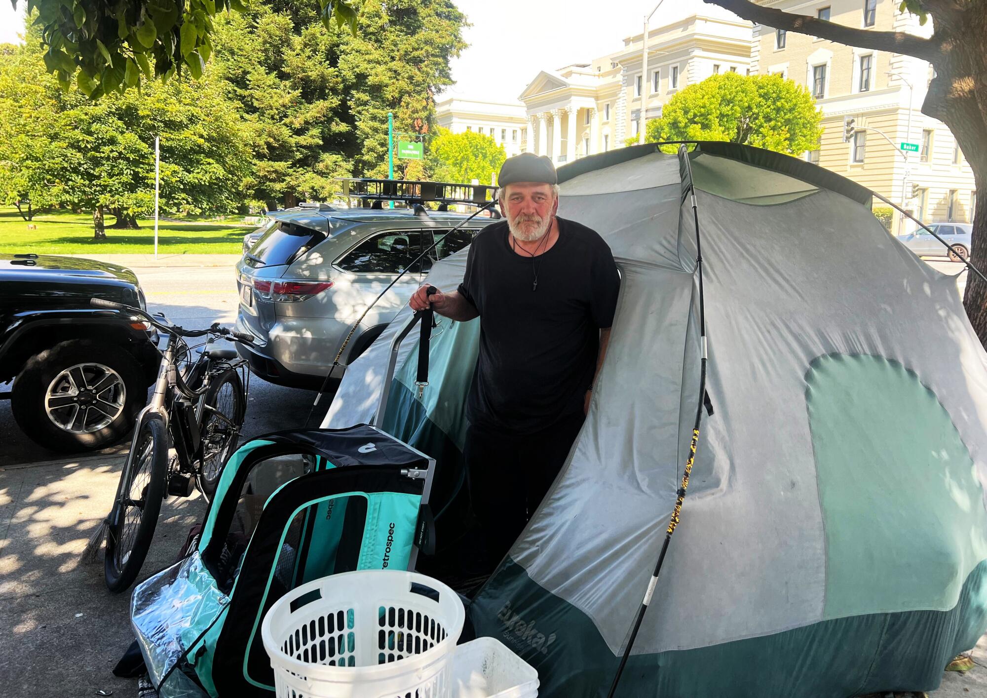 A man poses outside his tent pitched on a San Francisco sidewalk.