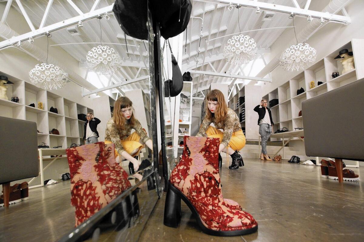 Sales associate Lucy Bull fixes a display with an embroidered runway boot by Ann Demeulemeester as store owner Lisa Bush checks inventory at III Luxury Collective, on Main Street in Venice.