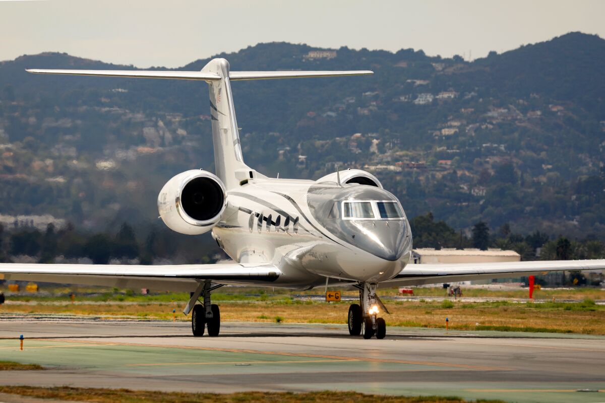 A jet taxis onto a runway in view of the Hollywood Hills.