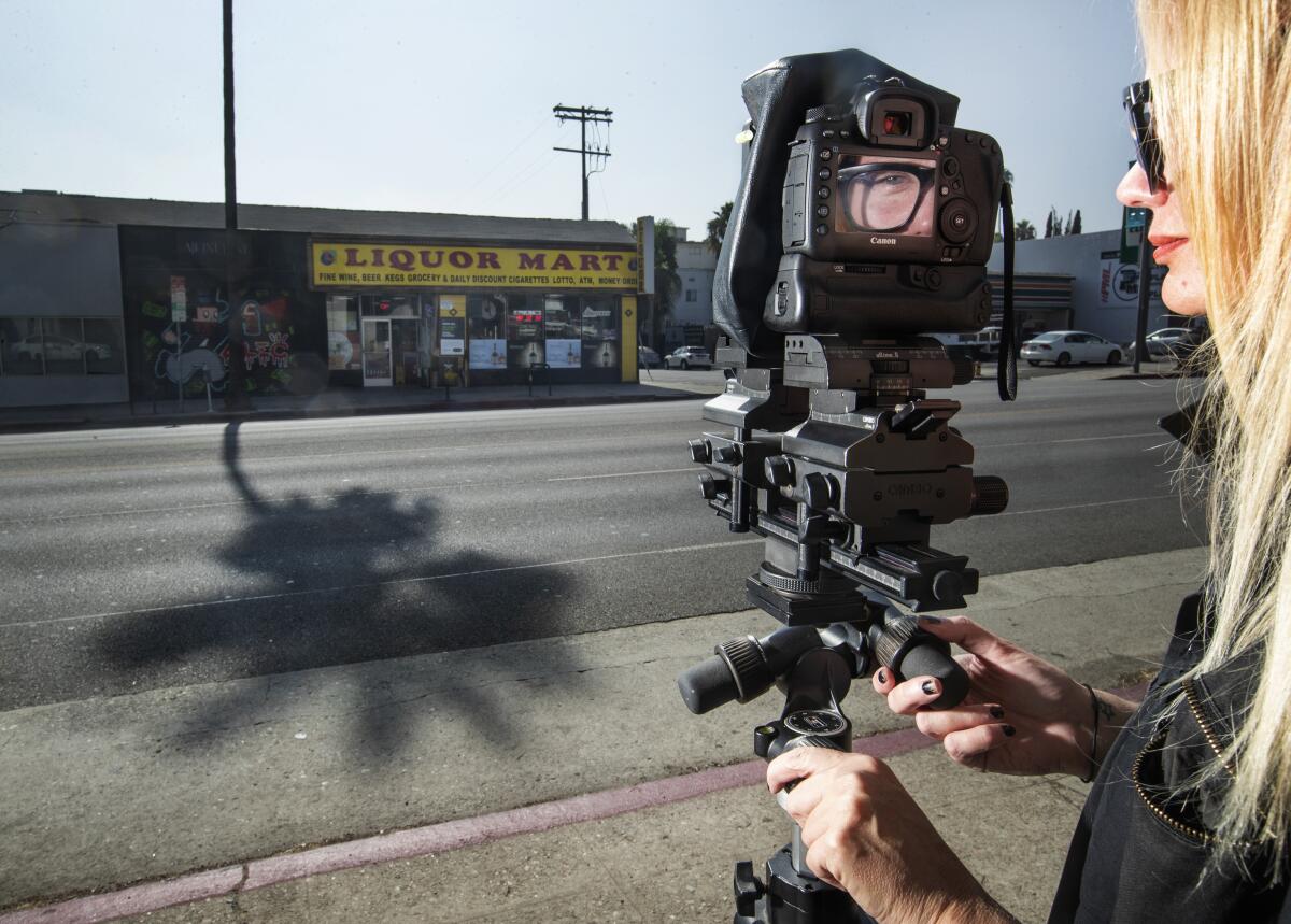 Ashley Noelle poses with her camera and tripod across the street from a storefront on Sunset Blvd. in Los Angeles, one of the kinds of places that she likes to document as quintessential L.A.