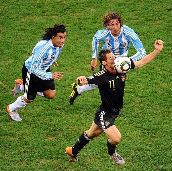 Germany's striker Miroslav Klose takes the ball as he is chased by Argentina's striker Carlos Tevez, left, and defender Gabriel Heinze during the 2010 World Cup quarterfinal match Saturday at Green Point stadium in Cape Town, South Africa.