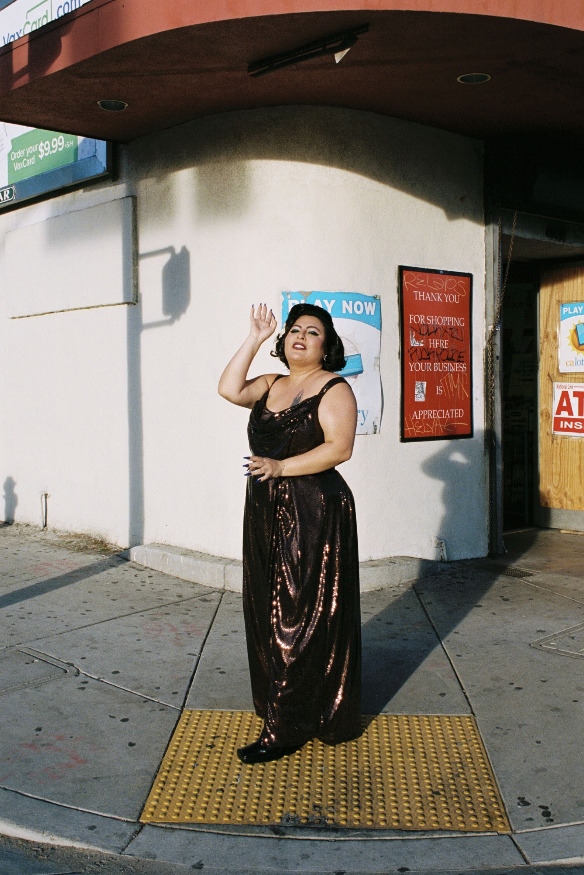 San Cha poses for a shoot in front of a store front.