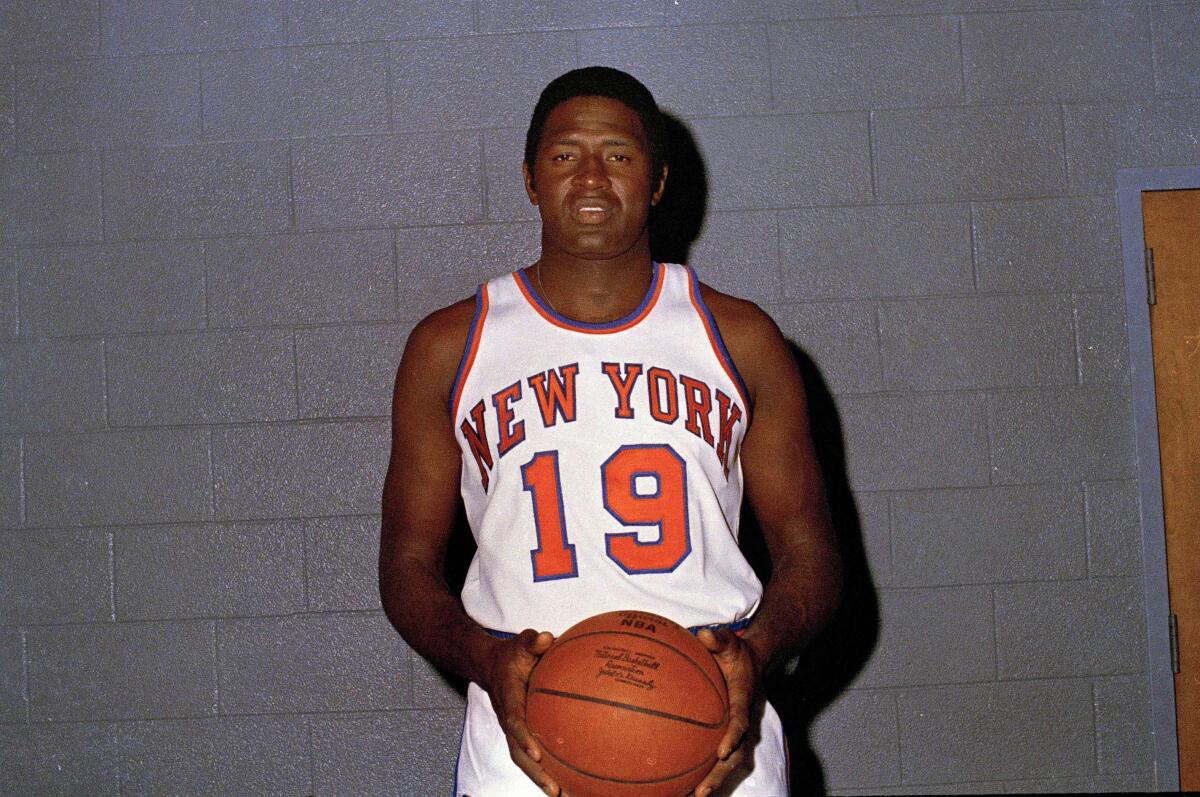 New York Knicks center Willis Reed poses for a photo in uniform while holding a basketball.