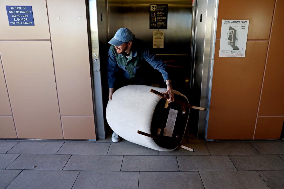 A person exits an elevator with a chair from the Wing in West Hollywood.