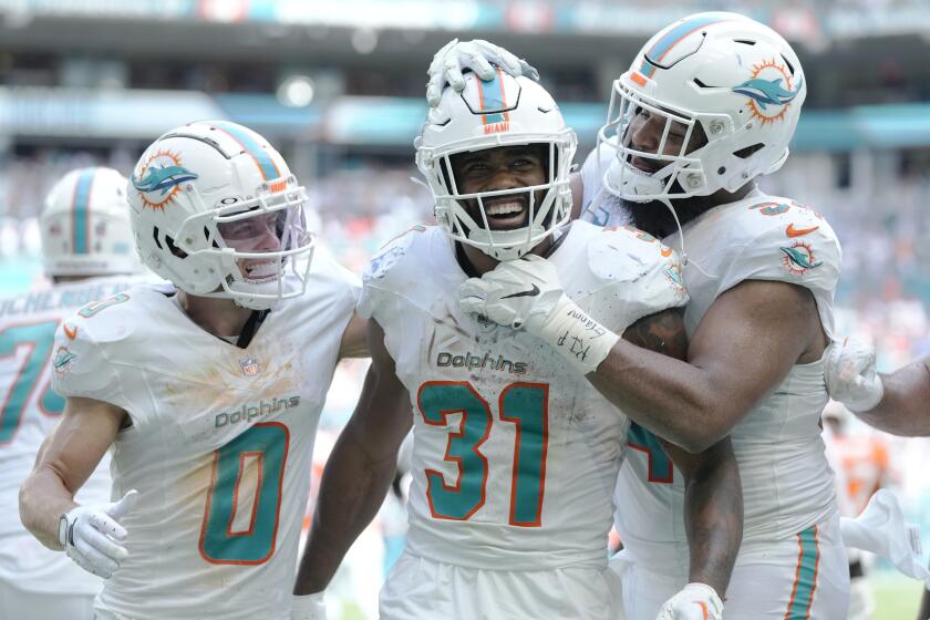 Miami Dolphins running back Raheem Mostert (31) is congratulated by wide receiver Braxton Berrios (0) and defensive tackle Christian Wilkins (94) after scoring a touchdown during the second half of an NFL football game against the Denver Broncos, Sunday, Sept. 24, 2023, in Miami Gardens, Fla. (AP Photo/Rebecca Blackwell)