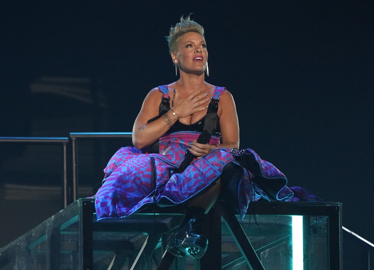 Pink performs while sitting on a stage platform and holding her right hand over her chest