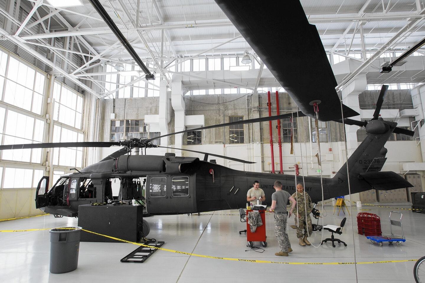 Sgt. Daniel Davis, left, Specialist Mark Enriquez, and Sgt. Sink Nuom, right, work on a UH-60 Black Hawk at the Los Alamitos Joint Forces Training Base on Monday.
