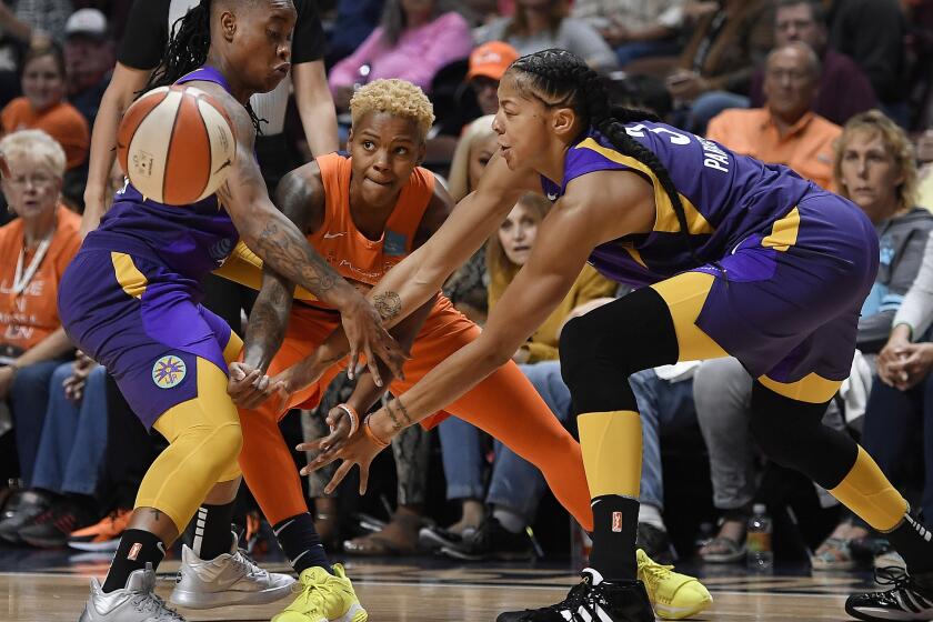 Connecticut Sun's Courtney Williams, center, passes between Los Angeles Sparks' Riquna Williams, left, and Candace Parker during the first half of Game 2 of a WNBA basketball playoff game Thursday, Sept. 19, 2019, in Uncasville, Conn. (AP Photo/Jessica Hill)