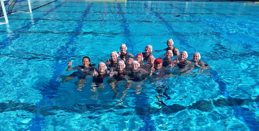 Coach David Bennett (red cap) celebrates title with the Santa Fe Christian girls water polo team.