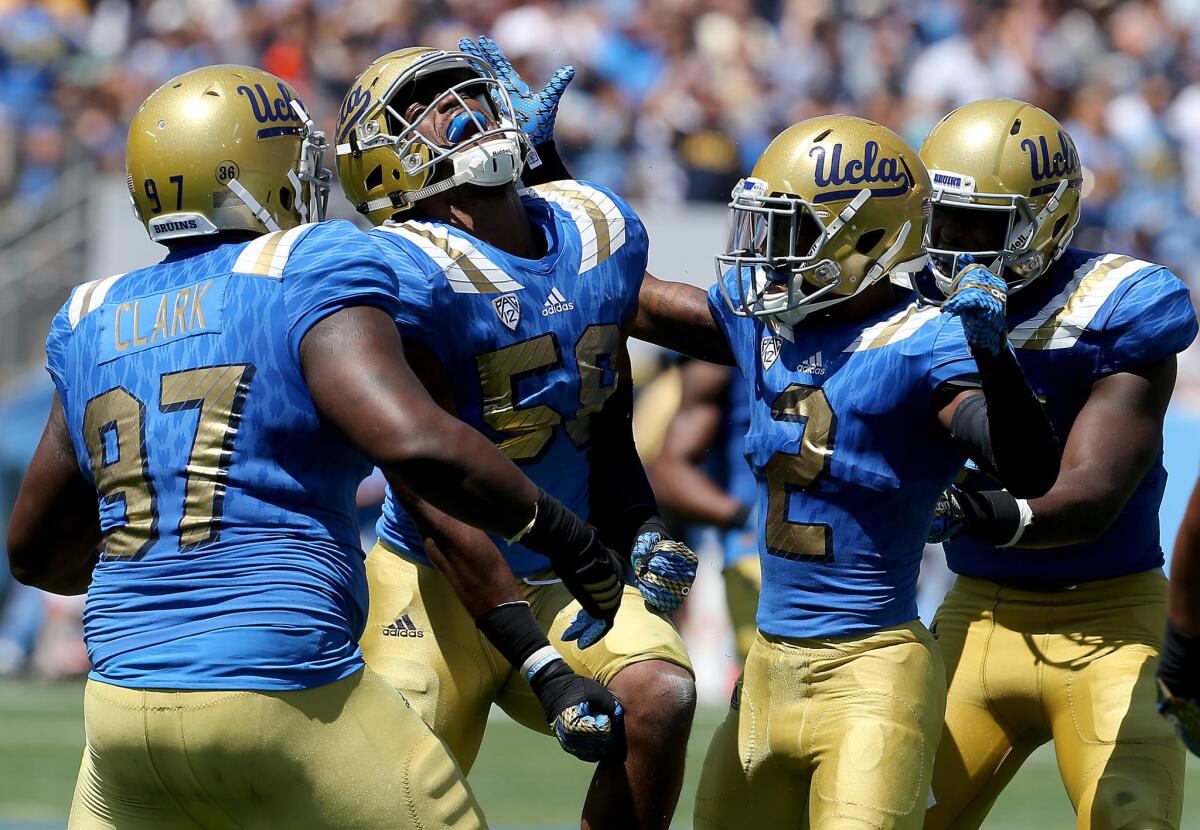 UCLA linebacker Deon Hollins (58) is congratulated by teammates after sacking Virginia quarterback Matt Johns in the first half on Sept. 5, 2015.