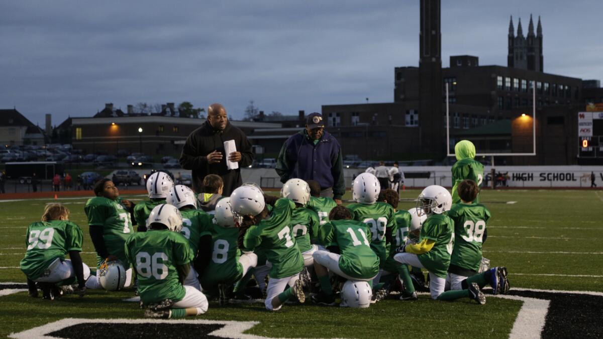 A coach speaks with players after a youth football game in Michigan on Tuesday.