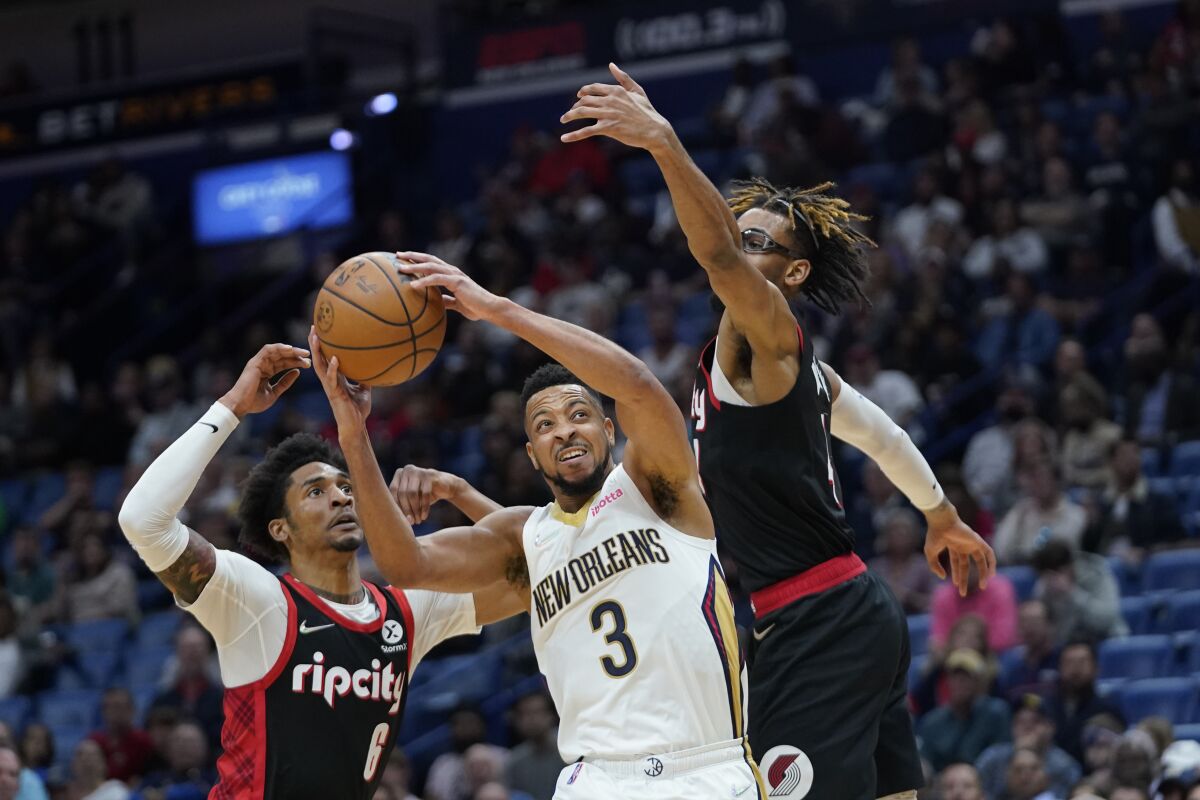 New Orleans Pelicans guard CJ McCollum (3) goes to the basket between Portland Trail Blazers guard Keon Johnson (6) and forward Greg Brown III in the second half of an NBA basketball game in New Orleans, Thursday, April 7, 2022. (AP Photo/Gerald Herbert)