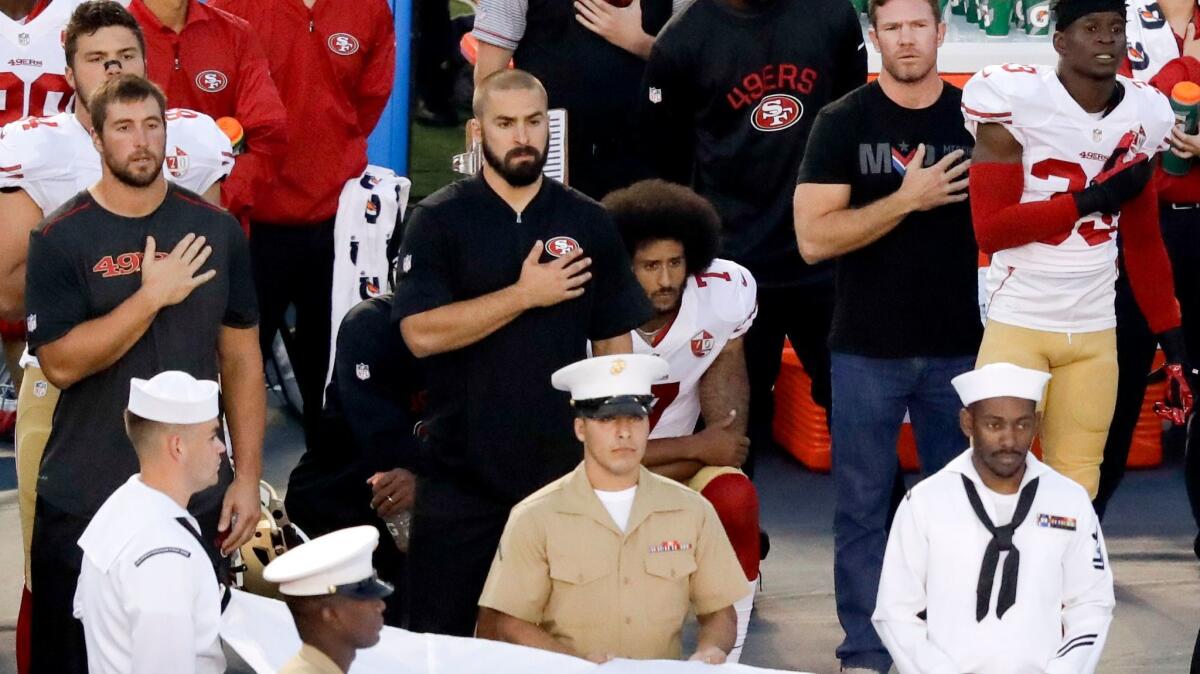 Colin Kaepernick, middle, kneels during the national anthem before the San Francisco 49ers' game against the San Diego Chargers on Sept. 1.